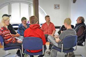 Ein Stuhlkreis von Menschen. Alle tauschen sich im Gespräch aus